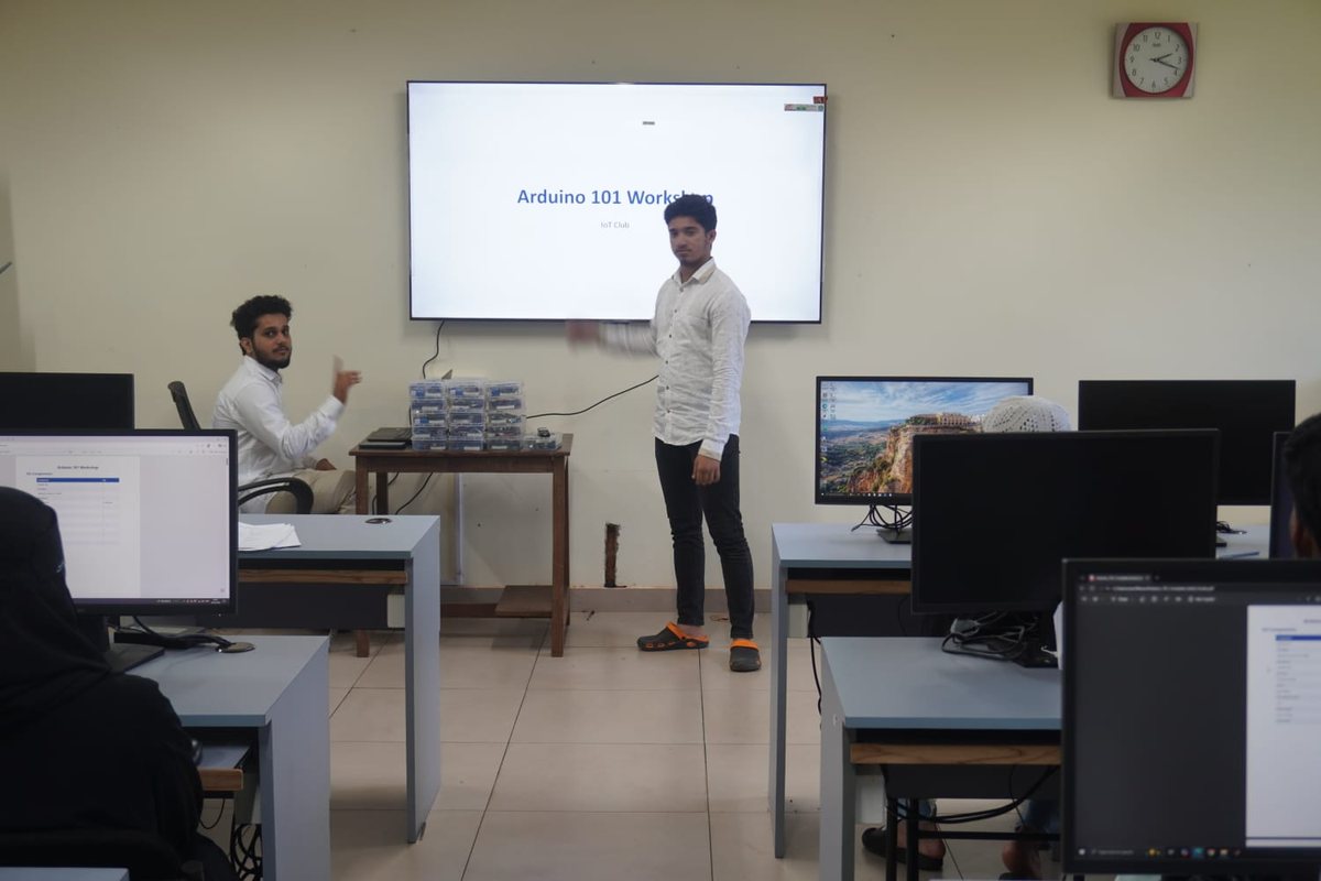 Standing beside the Arduino 101 Workshop title slide, kits stacked on the table